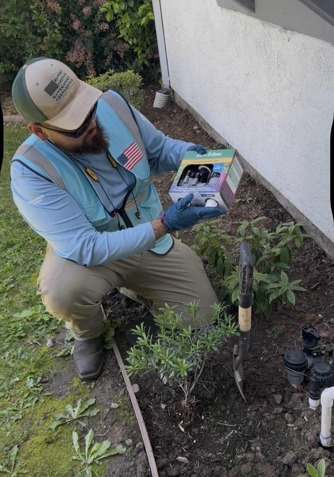 Eco-Scapes technician inspecting new Rain Bird sprinkler heads before installation in a Fairfield CA backyard