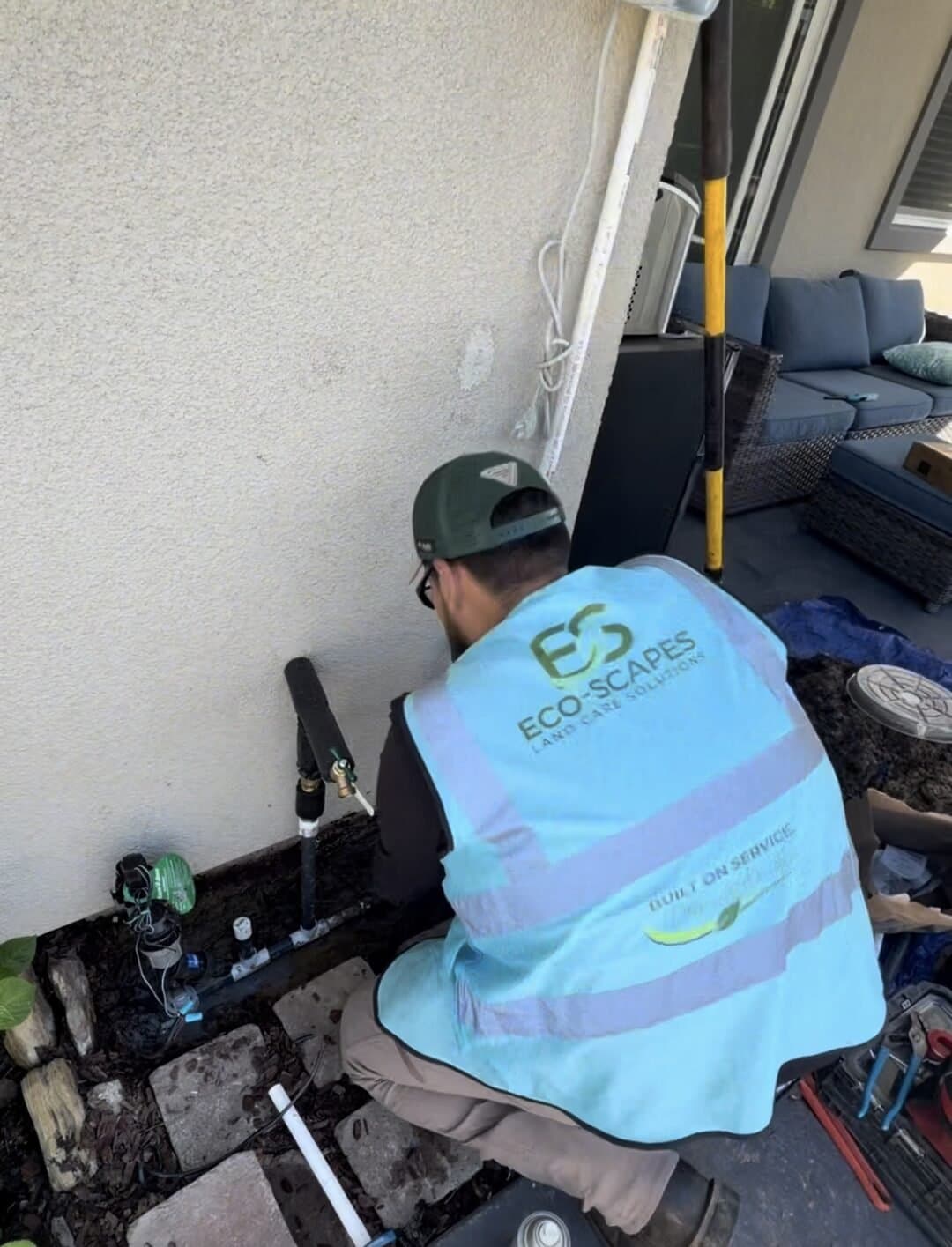 Eco-Scapes technician servicing hose bib and backflow plumbing at a Dixon CA home